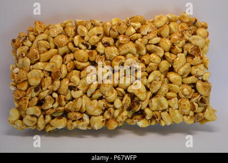 On a white paper background is located and placed from a delicious and sweet grilling of air corn kernels, popcorn with caramel Stock Photo