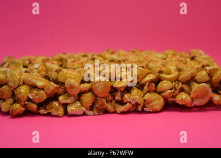 On a bright colorful pink paper background is located and placed from a delicious and sweet grilling of air corn kernels, popcorn with caramel Stock Photo