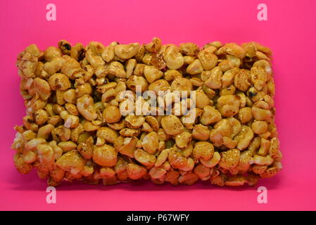 On a bright colorful pink paper background is located and placed from a delicious and sweet grilling of air corn kernels, popcorn with caramel Stock Photo
