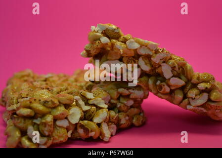 On a bright colorful pink paper background is located and placed from a delicious and sweet grilling of air corn kernels, popcorn with caramel Stock Photo