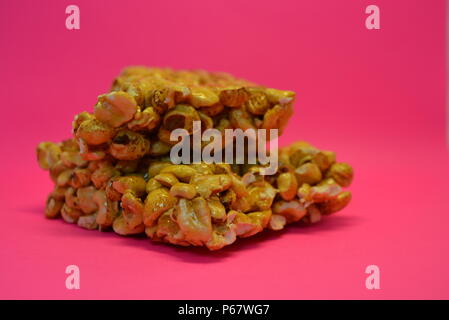 On a bright colorful pink paper background is located and placed from a delicious and sweet grilling of air corn kernels, popcorn with caramel Stock Photo