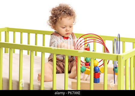 Baby boy playing with toys in a crib isolated on white background Stock Photo