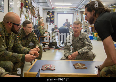 U.S. Air Force Master Sgt. Benjamin Thomas, of the 435th Contingency Response Group, converses with German paratroopers after a U.S./Deutschland Friendship Jump, Ramstein Air Force Base, May 25, 2016. The purpose of the friendship jump is to foster and nurture U.S. and German relationships, develop interoperability during training, and provide a basis for future operations in training and real world environments. (U.S. Army photo by Spc. Joseph Cathey/released) Stock Photo