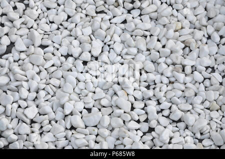 A lot of round and oval stones of white color lie on the ground in the garden . Stock Photo