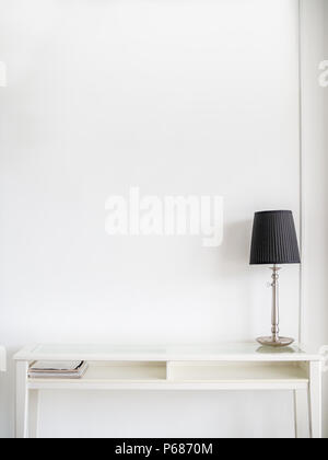 White Modern Book Table and Black Lamp on Clean White Wall Background with Copy Space. Stock Photo