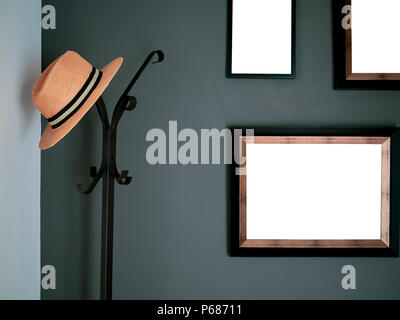 Orange Fashion Hat Hanging on Black Vintage Standing Hat and Coat Hanger with Blank Frames on The Dark Green Wall. Stock Photo