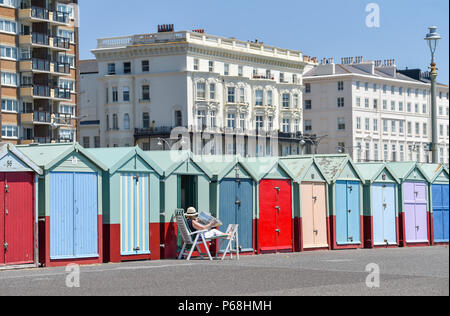 Hove Brighton UK 29th June 2018 - Sunbathers enjoy the beautiful hot sunshine by their beach huts on Hove  seafront as the heatwave continues throughout Britain Credit: Simon Dack/Alamy Live News Stock Photo