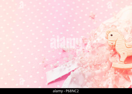 Girl pink felt background Baby Shower party with little rocking pony toy, lace and beads decor. Copy space. Top view. Stock Photo