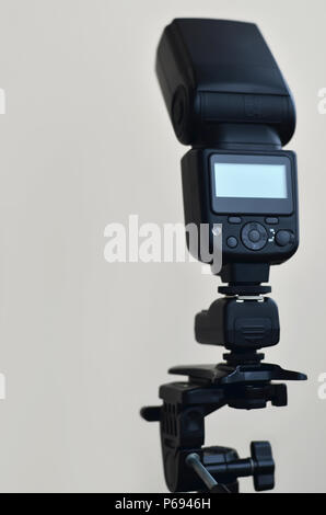 External photographic flashlight gun is mounted on the remote wireless control radio trigger set, which stands on a tripod. lighting equipment for stu Stock Photo