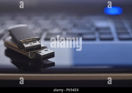 USB flash cards lying on black laptop case in front of his keyboard. Virtual memory storage with USB output Stock Photo