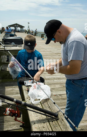 Father and son bait hooks for fishing on pier at Myrtle Beach State Park, SC, USA. Stock Photo