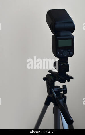 External photographic flashlight gun is mounted on the remote wireless control radio trigger set, which stands on a tripod. lighting equipment for stu Stock Photo