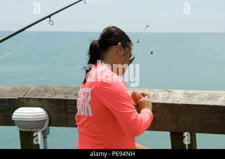 Woman baits hook for fishing on pier at Myrtle Beach State Park, SC, USA. Stock Photo