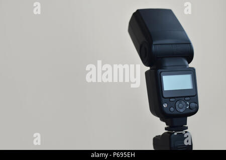 External photographic flashlight gun is mounted on the remote wireless control radio trigger set, which stands on a tripod. lighting equipment for stu Stock Photo