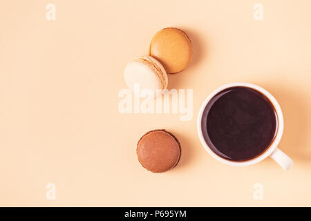 Cup of coffee with macaroons on pastel background, flat lay. Stock Photo