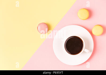 Cup of coffee with macaroons on pastel background, flat lay. Stock Photo
