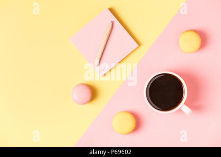 Cup of coffee with macaroons on pastel background, flat lay. Stock Photo