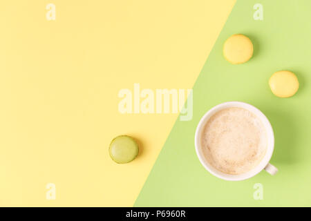 Cup of coffee with macaroons on pastel background, flat lay. Stock Photo