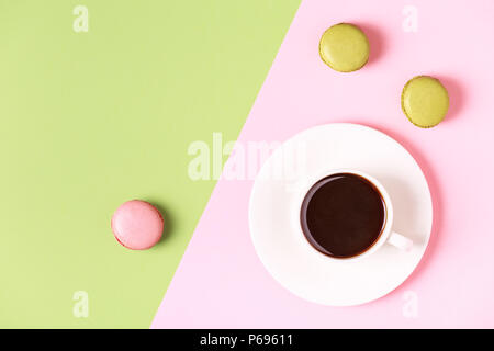 Cup of coffee with macaroons on pastel background, flat lay. Stock Photo