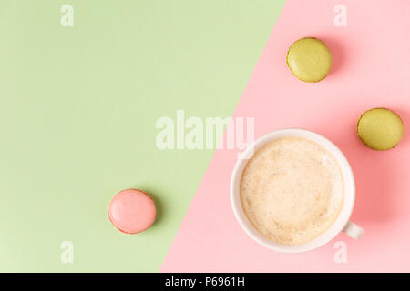 Cup of coffee with macaroons on pastel background, flat lay. Stock Photo