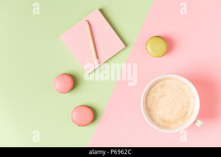 Cup of coffee with macaroons on pastel background, flat lay. Stock Photo