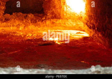 looking inside an aluminum melting furnace, in a foundry, with liquid metal and the oxidize dross layer on it Stock Photo