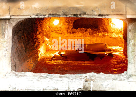 looking inside an aluminum melting furnace, in a foundry, with liquid and solid pieces of metal Stock Photo