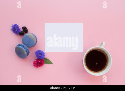A cup of black fresh coffee, macaroons, berries and beautiful flowers on pastel pink background with text space. Stock Photo