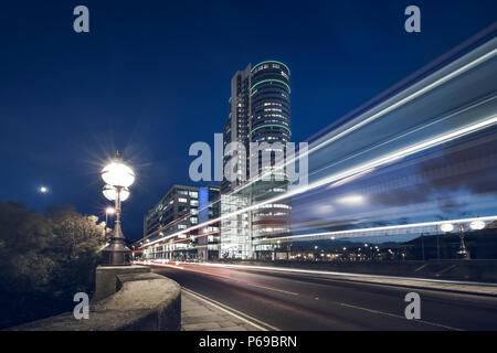 Dusk in Leeds, UK. Traffic leaves light trails with Bridge water place in the background. Stock Photo