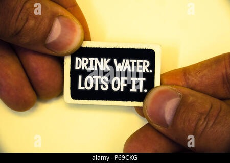 Word writing text Drink Water. Lots Of It. Business concept for drinking liquids to keep our body in great status Two hands hold small black card focu Stock Photo