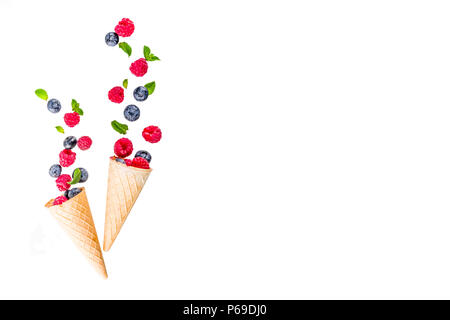 Creative layout with raspberry and blueberry with waffle ice cream cones, simple pattern above copy space Stock Photo