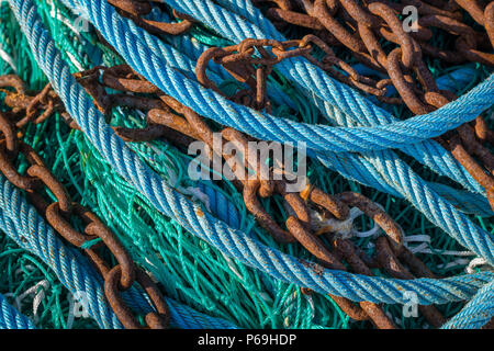 Abstract of various blue, green ropes and rusty chains lying on a fishing boat Stock Photo