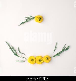 Flowers composition. Wreath made of various yellow flowers and green leaves and branches on pastel yellow background. Flat lay, top view, copy space,  Stock Photo