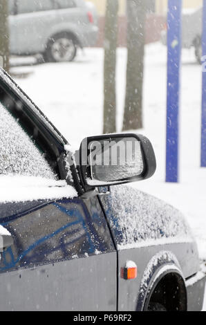 Fragment of the car under a layer of snow after a heavy snowfall. The body of the car is covered with white snow . Stock Photo