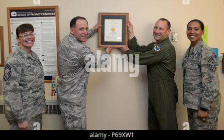 Col. Gentry Boswell, 28th Bomb Wing commander, center right, and Col. Christopher Dun, 28th Medical Group commander, center left, are joined by Chief Master Sgt. Sonia Lee, 28th BW command chief, right, and Chief Master Sgt. Tracy House, 28th MDG superintendent, left, to hang a Joint Commission accreditation certificate in the 28th MDG lobby at Ellsworth Air Force Base, S.D., May 26, 2016. The Joint Commission, an independent, not-for-profit organization, accredits and certifies nearly 21,000 health care organizations and programs in the U.S. Accreditation from the Joint Commission is recogniz Stock Photo