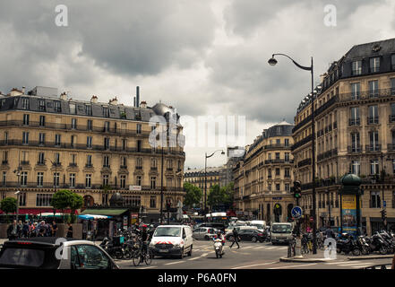 Paris apartment buildings in the Haussmann-style surround a street busy with traffic in Paris, France. Stock Photo