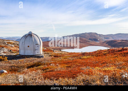 Metal US bunker and autumn greenlandic orange tundra landscape with lakes and mountains in the background, Kangerlussuaq, Greenland Stock Photo