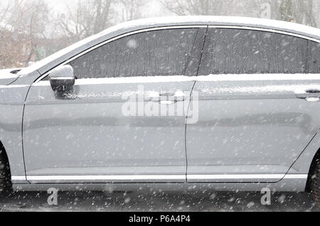 Fragment of the car under a layer of snow after a heavy snowfall. The body of the car is covered with white snow . Stock Photo