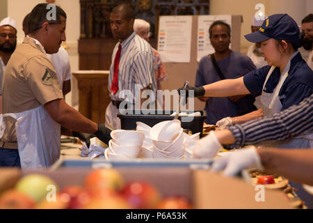 U.S. Marine Corps Lance Cpl. Alejandro Olivarez, left, motor transportation operator with Headquarters and Support Company, 3rd Battalion, 6th Marine Regiment, and U.S. Coast Guard Lt. Cmdr. Mimi Moon, port state control chief with Sector New York, serve food at the Holy Apostles Soup Kitchen in New York, May 27, 2016 during Fleet Week. U.S. Marines, sailors and coast guardsmen visited the city to interact with the public, demonstrate capabilities and teach the people of New York about America's sea services. (U.S. Marine Corps photo by 24th MEU Combat Camera Lance Cpl. Hernan Vidana/Released) Stock Photo