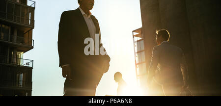 Men in formal clothes commuting to office early in the morning carrying office bags. Businessmen in hurry to reach office walking on city street with  Stock Photo