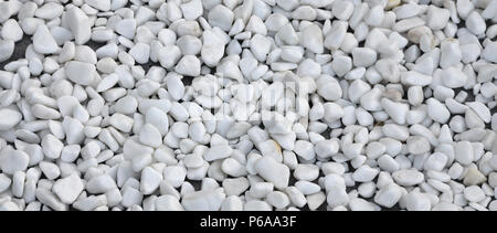 A lot of round and oval stones of white color lie on the ground in the garden . Stock Photo