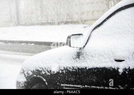 Fragment of the car under a layer of snow after a heavy snowfall. The body of the car is covered with white snow . Stock Photo