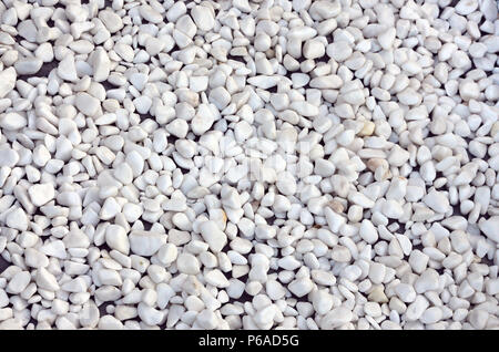 A lot of round and oval stones of white color lie on the ground in the garden . Stock Photo