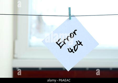 Error 404. Note is written on a white sticker that hangs with a clothespin on a rope on a background of window glass . Stock Photo
