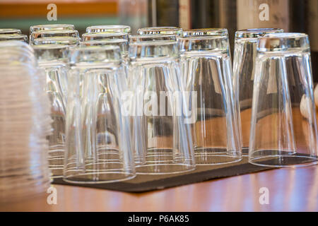 Empty glasses for juice at the bar. Stack of cleaned glasses on bar counter, catering service at company party.Selective focus.Preparing for party. Many clean shiny empty glasses Stock Photo