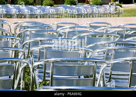 Rows of empty metal chair seats installed for some business event or performance,festival.Many empty parallel arranged silver chairs.conference chair prepare to use. Stock Photo