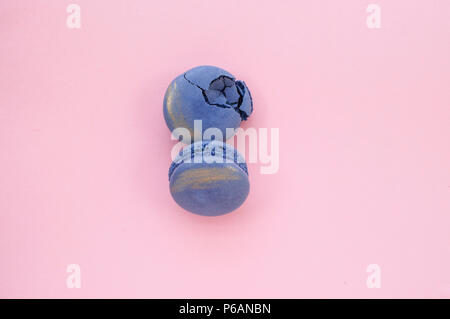 Two beautiful and tasty violet color macaroons with golden stroke on pink background. Stock Photo