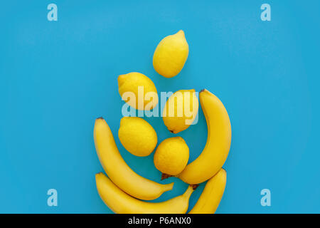 yellow bananas and lemons on bright blue paper, trendy flat lay. fruits modern image, top view. juicy summer vitamin abstract background. pop art styl Stock Photo