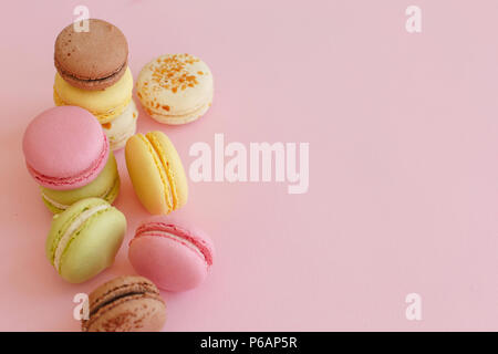 food photography of tasty colorful macarons  on trendy pastel pink paper. space for text pink, yellow, green, white, brown macaroons. yummy background Stock Photo