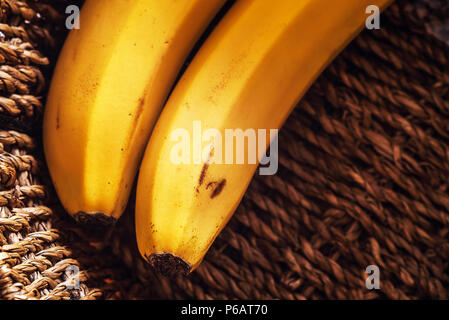 Abstract composition of two vividly yellow bananas in basket. Stock Photo